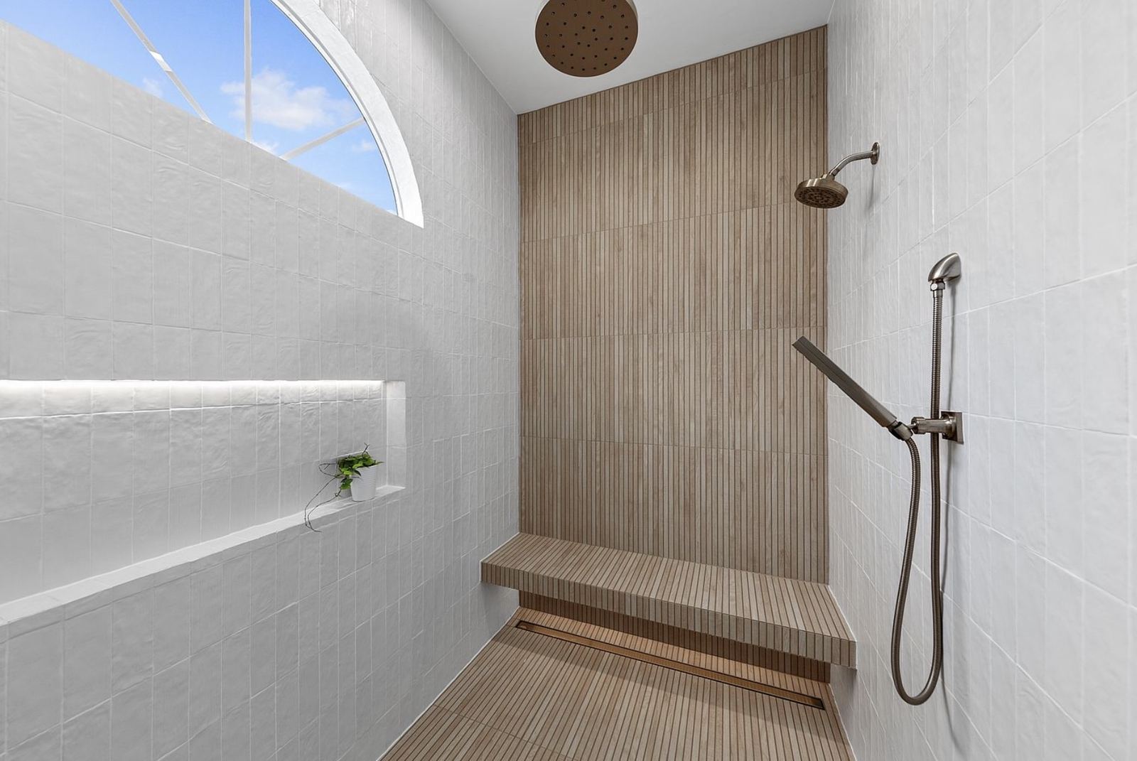 Finished walk-in shower with wood-look slat tile and brass fixtures
