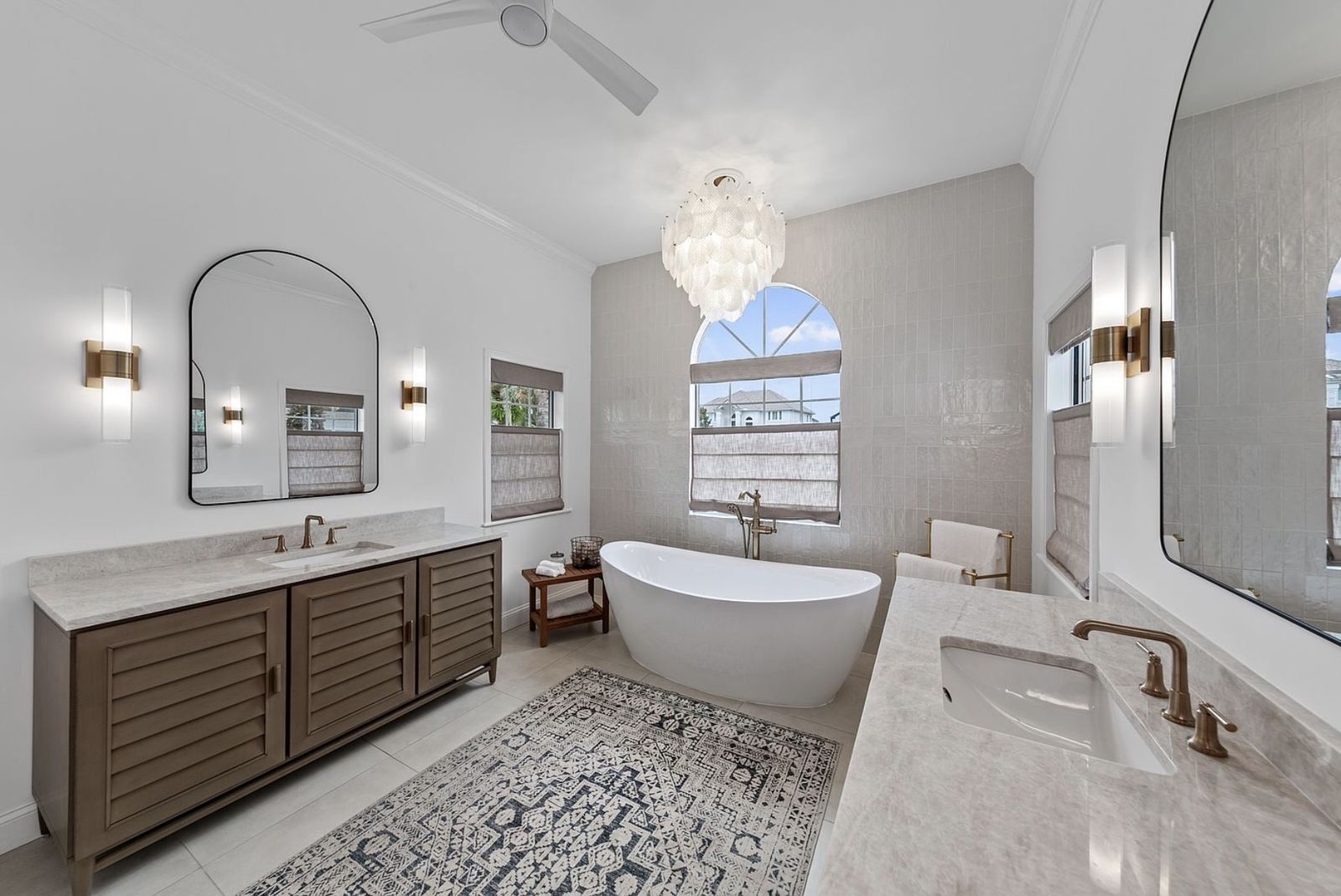 Finished primary bath with tub, dual vanity, and chandelier