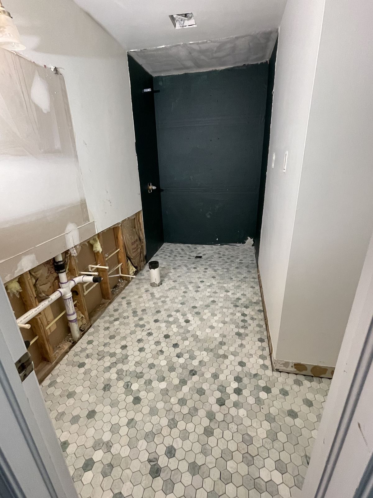 Bathroom stripped to studs with hexagon floor tile installed