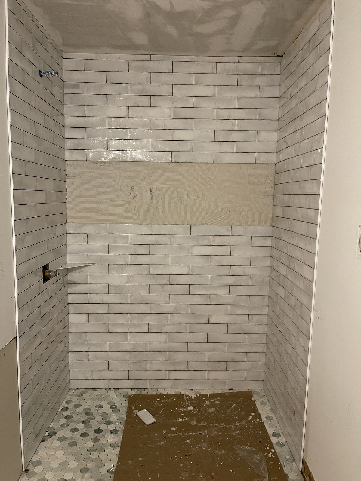 Subway tile installation in progress with mosaic accent band