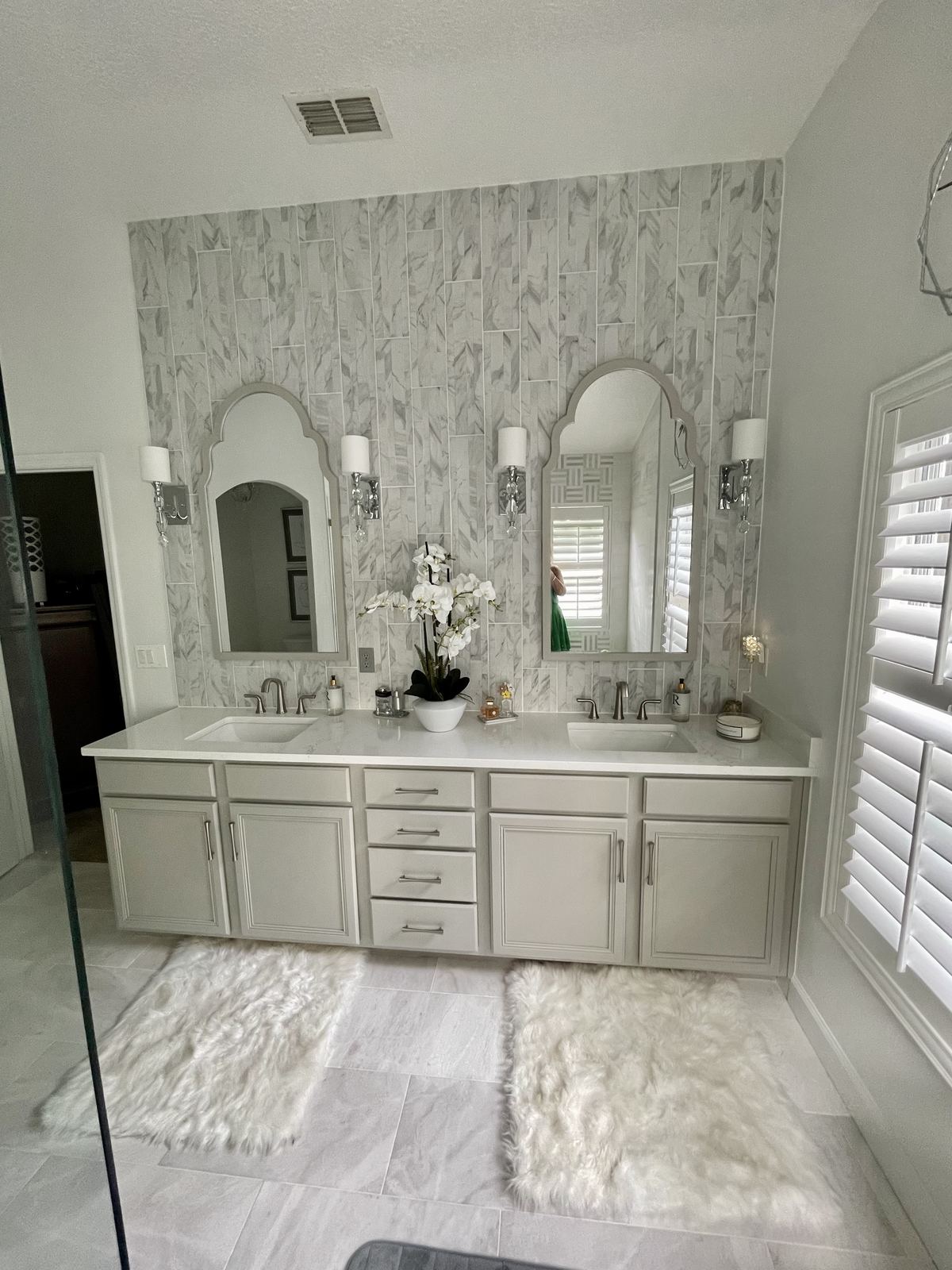 Finished dual vanity with arched mirrors and vertical marble tile