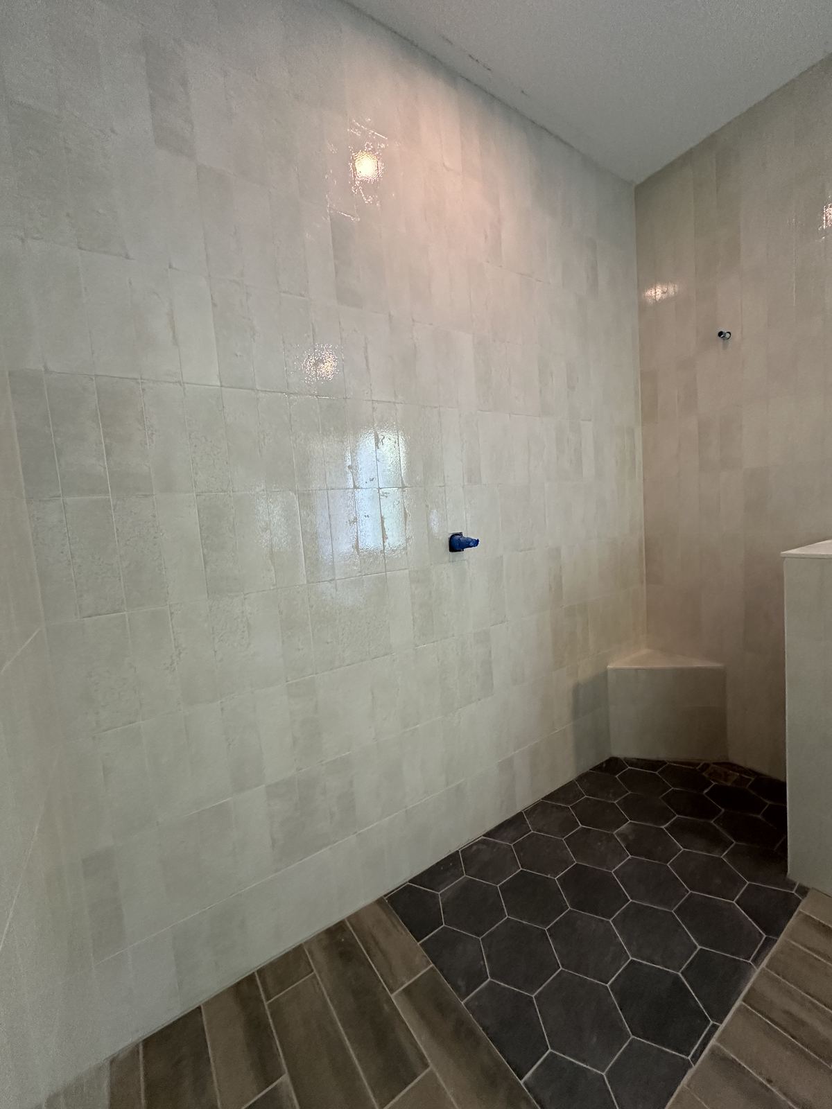 Finished walk-in shower with hexagon tile floor and vertical wall tile