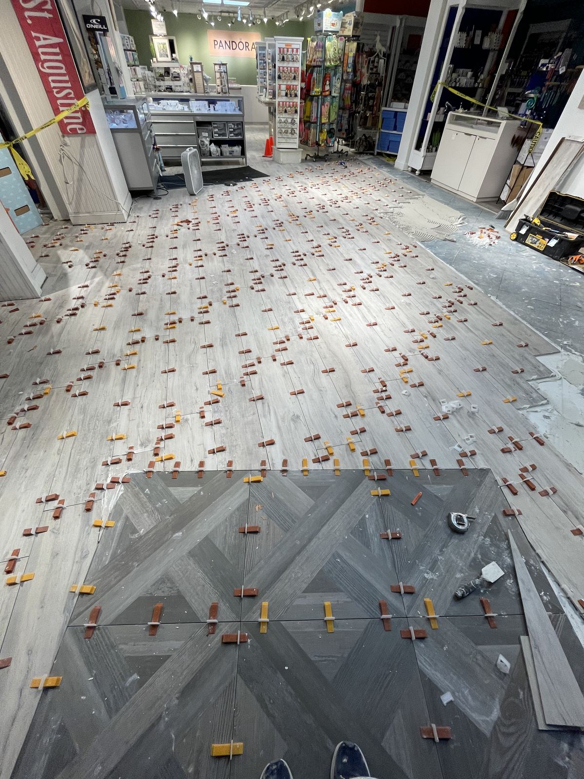 Wood-look tile installation with leveling clips across retail floor